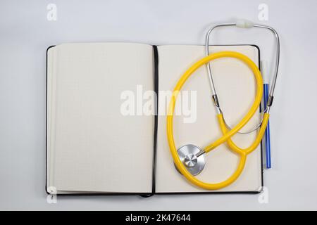 blank white paper notebook with a blue ink pen, Stethoscope, pen, and blank prescription pad. Medicine or pharmacy. Empty medical form ready to be used Stock Photo