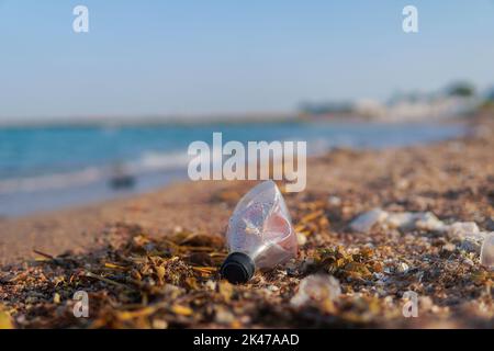throw the cruttled bottle on the shore of the sea. ecology concept. garbage. Stock Photo