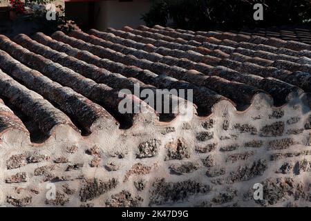 Roof tiles with lichens of an old traditional Spanish village house.   Old Tile Roof Texture Spain. Alcudia old tile roof. Stock Photo