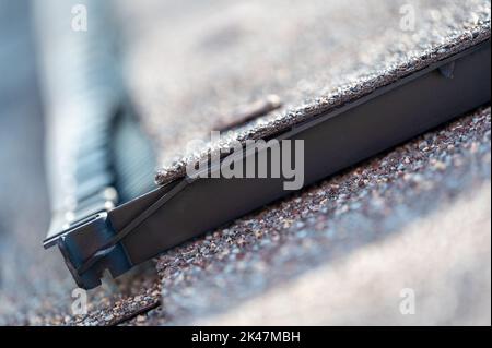 Ridge cap vent installed on a shingle roof for passive attic ventilation on a residential house.  Stock Photo