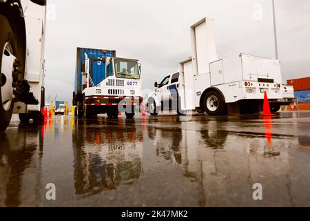 A shipping container pulled by a port vehicle is scanned by truck-mounted radiation detection systems operated by U.S. Customs and Border Protection officers at the Port of Miami in Miami Fla., Dec. 07, 2015. U.S. CBP Photo by Glenn Fawcett Stock Photo