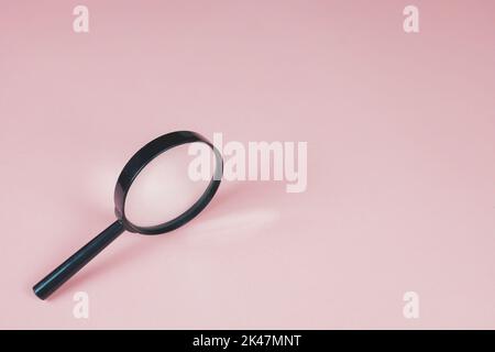 Magnifying glass on the pink background. Light is refracted through glass of magnifier. Copy space for text. Finding and zooming concept. Lens, loupe. Stock Photo