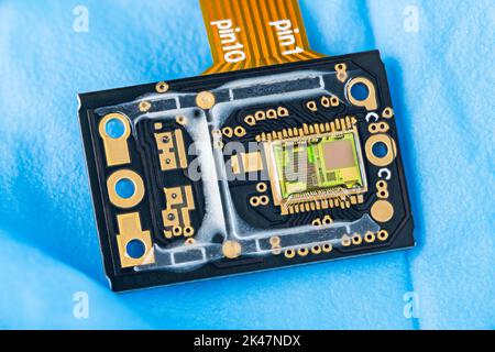 Green silicon die with photodiodes array on electronic PCB detail with orange flex cable. Modern image sensor inside a chip of optical computer mouse. Stock Photo