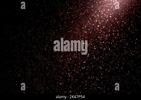 Dust particles on black background with light ray. Purple glittering sparkling flickering glowing dots. Stock Photo