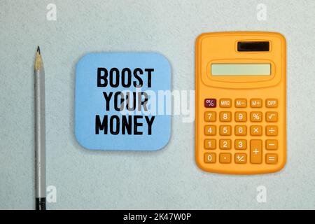 Text sign showing Boost Your Money. Conceptual photo increase your bank saving using effective methods. Text written in notebook with pen, calculator, Stock Photo