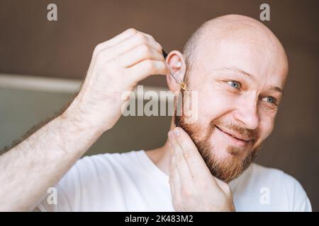 Adult handsome man with pipette with beard oil in bathroom at home Stock Photo