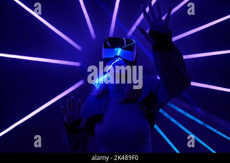 Woman is using virtual reality headset to access in metaverse. Concept of virtual, augmented and extended reality, future technology, artificial intel Stock Photo