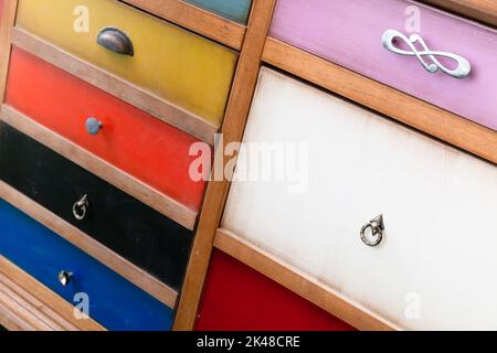 Commode drawers with colorful panels and different types of handles, close-up photo Stock Photo