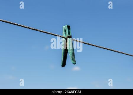 plastic clothespin hanging on a clothesline against a blue sky. Stock Photo