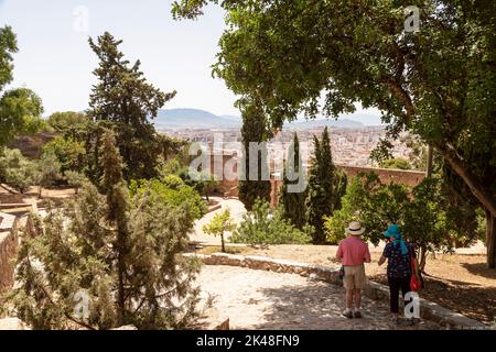 Two elderly tourists walk across the historic courtyard of the Castle of Gibralfaro (Castillo de Gibralfaro) in the city of Málaga in Spain. Stock Photo