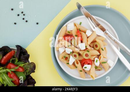 Red lentil penne salad on duo colour background Stock Photo