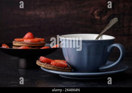Blue cup and saucer with chocolate biscuits and strawberries Stock Photo