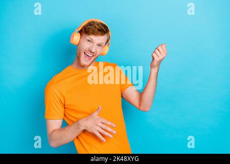 Photo of cheerful positive guy enjoy good music have fun relax dream music contest stand empty space isolated on cyan color background Stock Photo