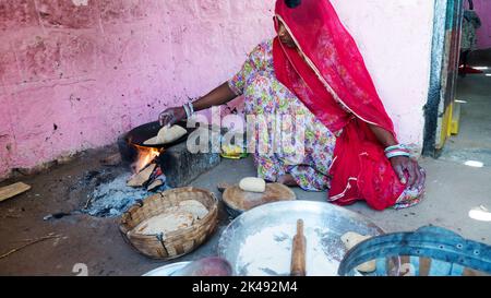 Bhinmal Rajasthan, India - May 23, 2017 : indian rural village woman preparing roti or chapatti food on traditional wood stove. Stock Photo