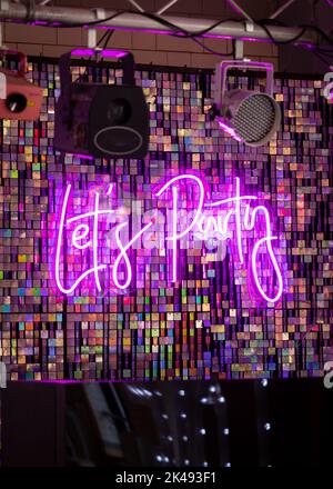 Lets Party neon light up sign on dance floor part for wedding first dance.  Purple text. Stock Photo