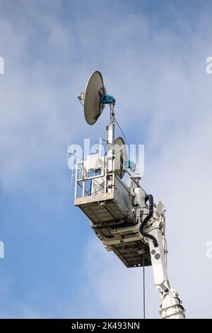 Satellite communications system raised on platform to relay HD and 4K television video at outdoor event Stock Photo