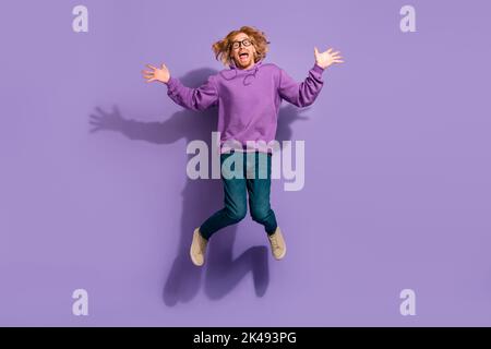 Full body photo of impressed beard red hair guy jump wear eyewear sweatshirt jeans shoes isolated on purple background Stock Photo