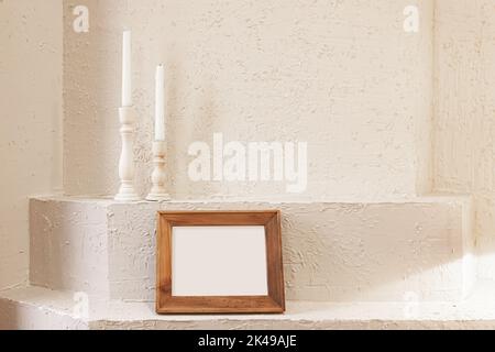 Photograph of horizontal wood frame mockup and candles on white plaster wall background Stock Photo