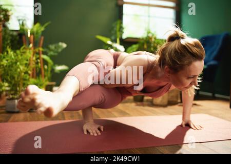 modern 30 years old woman with yoga mat meditating in the modern green living room. Stock Photo