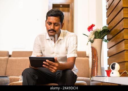 closeup shot of indian installing cctv camera by using mobile at home - concept of surveillance, safety and technology Stock Photo