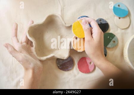 Woman holds handmade plate and paint swatches in her palms Stock Photo