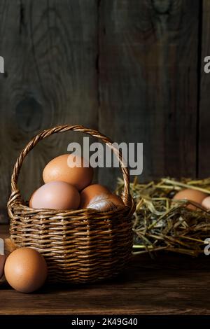 chicken eggs in wicker basket and in hay Stock Photo