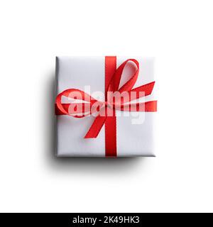 White gift box with red ribbon bow isolated on white background. Creative Christmas and Valentines Day postcard design Stock Photo