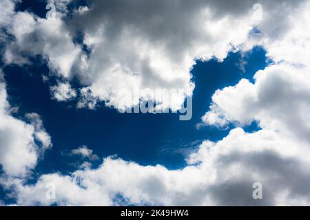 Blue sky and fluffy clouds illuminated by the day sun light. Nature background Stock Photo