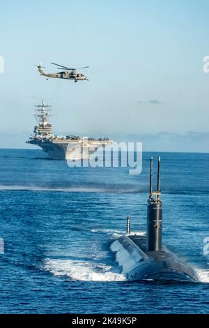 Busan, South Korea. 30th Sep, 2022. A U.S. Navy MH-60S Sea Hawk attached to the Golden Falcons of Helicopter Sea Combat Squadron 12, flys over a formation of the Nimitz-class, nuclear-powered super-carrier, USS Ronald Reagan led by a Los Angeles-class fast-attack submarine with Submarine Group Seven during joint training operations with the South Korean Navy in the East Sea, September 30, 2022 near Busan, South Korea. Credit: MC3 Gray Gibson/US Navy Photo/Alamy Live News Stock Photo