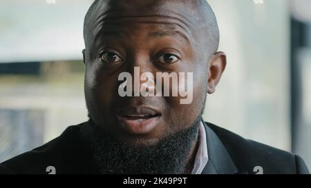 Positive cheerful adult male worker businessman african american employee brunet bearded guy satisfied client rejoice victory in office say wow Stock Photo