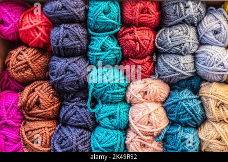 Coloured Balls of wool stacked on a shelf Stock Photo