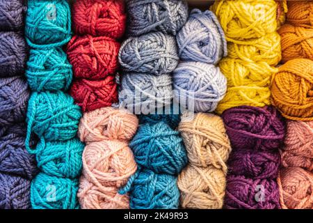 Coloured Balls of wool stacked on a shelf Stock Photo