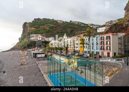 The Ponta do sol beach with palm trees and colorful houses in the east of Madeira in summer. Stock Photo