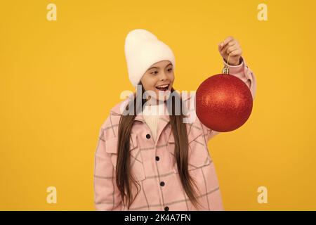 merry christmas. amazed kid in winter hat. teen girl with red decorative ball Stock Photo
