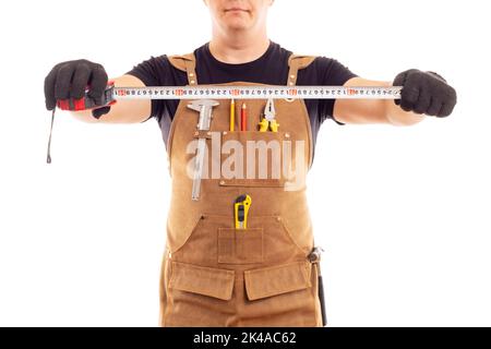Carpenter in workers apron is holding measuring tape on white background Stock Photo