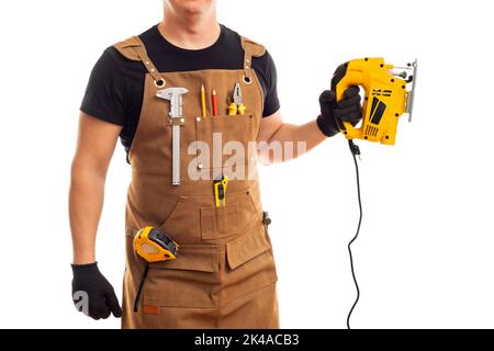 Carpenter in workers apron holding electric jig saw on white background Stock Photo
