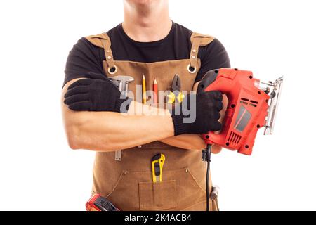 Carpenter in workers apron holding electric jig saw on white background Stock Photo