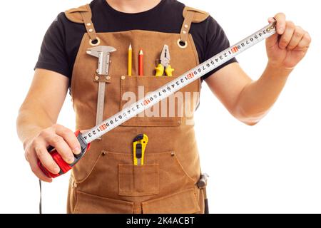 Carpenter in workers apron is holding measuring tape on white background Stock Photo