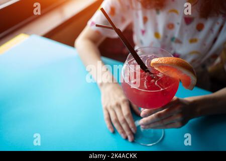 female drinking red grapefruit juicy cocktail with straw in cafe or restaurant Stock Photo