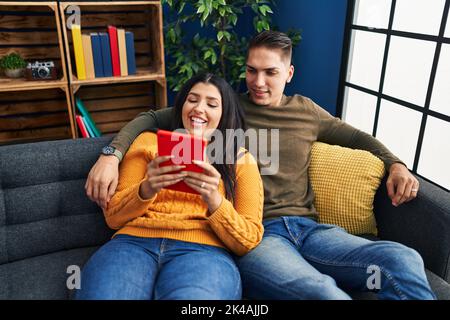 Man and woman couple hugging each other using touchpad at home Stock Photo
