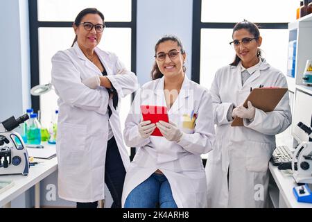 Three woman scientists using touchpad write on checklist at laboratory Stock Photo