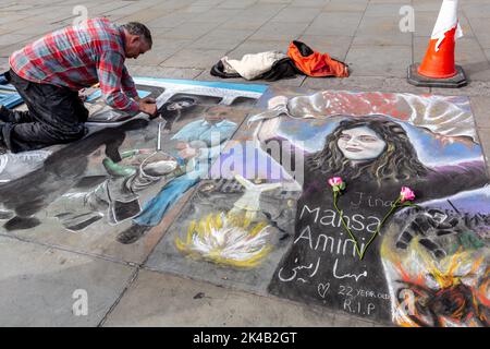 A man draws on a pavement during a demonstration in solidarity with Iranian women, as part of planned worldwide protests against the regime of the Islamic Republic of Iran after the death of Mahsa Amini. The death of Mahsa Amini, 22, from Kurdistan, who was arrested by the morality police in Tehran for not wearing her hijab correctly sent a wave of protests in Iran and across the world. Amini was taken to a detention center where she collapsed and died later in a hospital. The reason for her death is unclear. Iranian President Ebrahim Raisi promised a 'transparent investigation' last week. Stock Photo