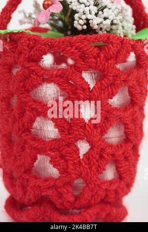 A flower pot in a knitted cover. It occupies the entire surface of the image. Close-up. Stock Photo