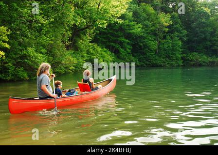 A family with a young child explores a lake and stream  in a canoe on a beautiful summer vacation dahy Stock Photo