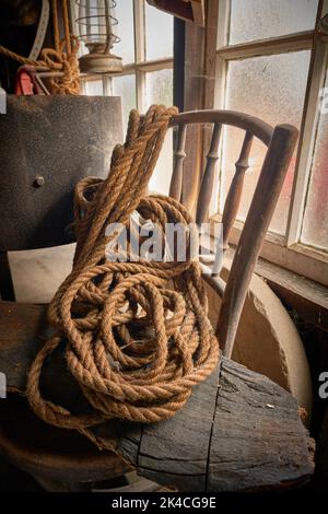 A vertical of an old rope hung over a broken wooden chair Stock Photo