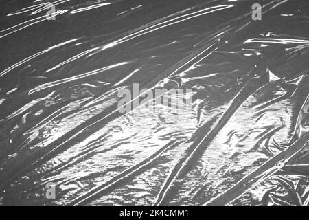 Reflecting light and shadow on creases and folds in plastic sheeting. monochrome light and texture, abstract background image. Stock Photo