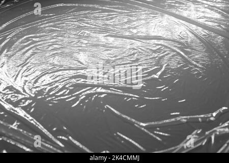 Reflecting light and shadow on creases and folds in plastic sheeting. monochrome light and texture, abstract background image. Stock Photo