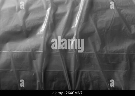 Reflecting light and shadow on creases and folds in plastic sheeting. monochrome light and texture, abstract background image. Stock Photo