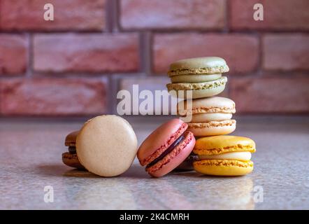 Variety of french macarons against a brick backdrop Stock Photo