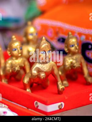 A vertical shot of small golden souvenirs of Lord Krishna in the streets of India Stock Photo